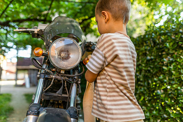 Toddler boy riding a balance bike (run bike), learning to keep balance on a training bicycle in the garden. Activity for children.