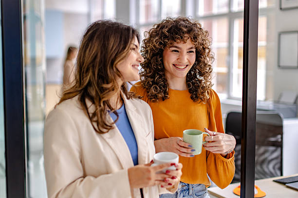 istock Two colleagues share a light moment in a modern office while enjoying coffee during a busy workday 2225380112