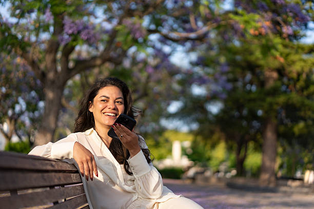 istock Woman recording audio message on park bench 2225381701