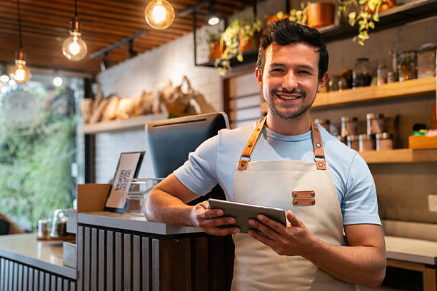 istock Happy waiter working at a cafe using a digital tablet and smiling 2225385047