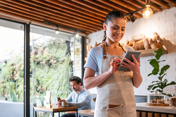 istock Happy waitress working at a coffee shop using a digital tablet 2225385144