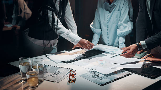 istock Business, hands and teamwork with documents in office for tax preparation, financial analysis or overtime. Accountant, people and discussion at night for finance statement review or auditing deadline 2225386935