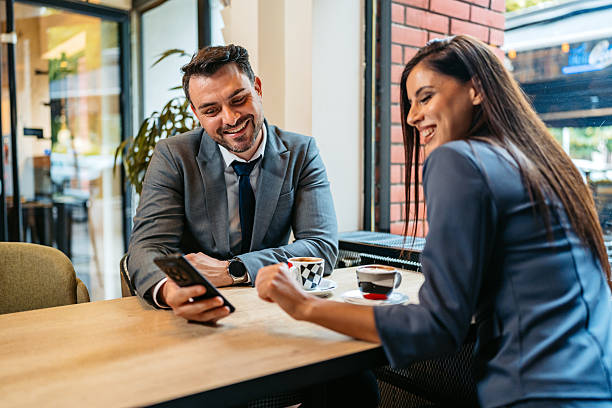 istock Two Business Colleagues Using A Phone Together While Drinking Coffee In A Coffee Shop 2225388172