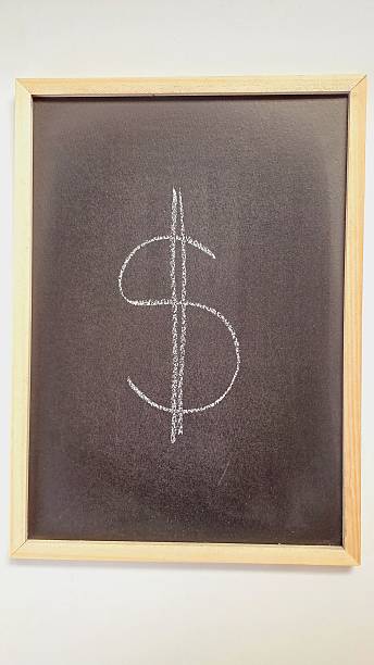 Dollar sign handwritten with white chalk on a wooden framed blackboard.
