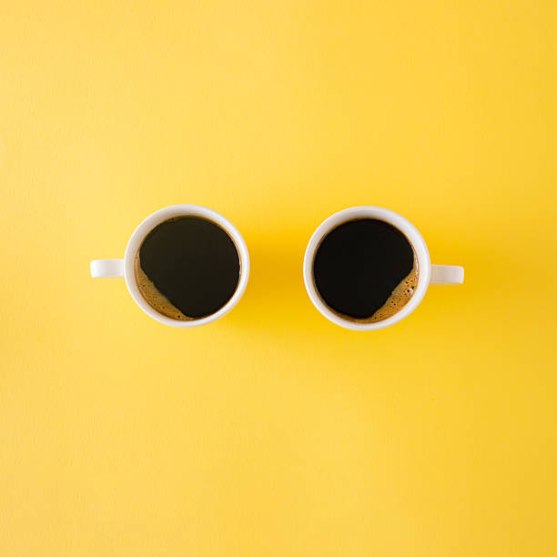 istock Creative concept made with two white cup of morrning coffee on a yellow backround with copy space.Minimal flat lay 2225397507