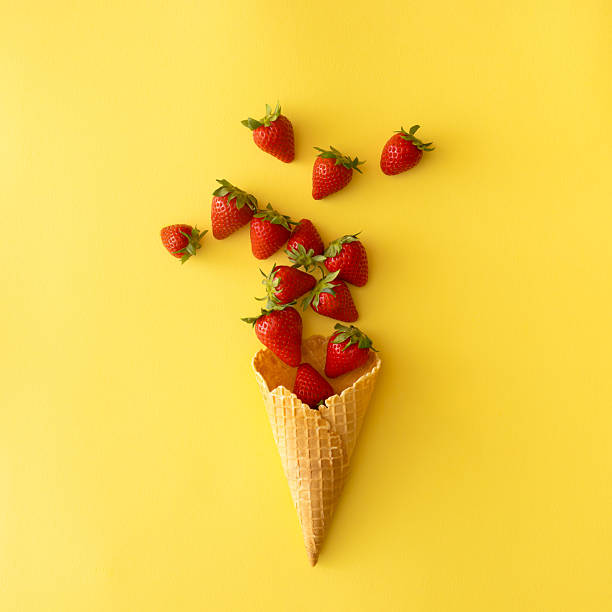 istock Ice cream cone with strawberries on a yellow backround.Creative food concept 2225398338