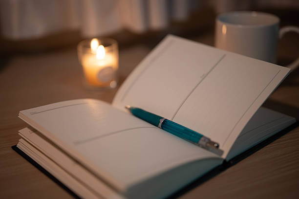 istock Notebook and pen on a desk, a lit candle and a coffee cup. 2225398585