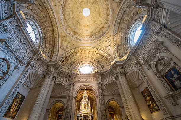 Sevilla, Spain - March 10, 2025: Ornate dome with stained glass and detailed altar. High columns and religious art enhance the scene. Largest Gothic cathedral and UNESCO site.