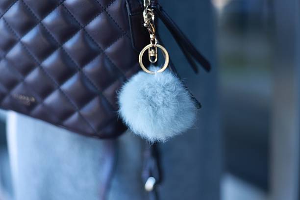 Woman with faux fur keychain on her backpack outdoors, closeup. Selective focus