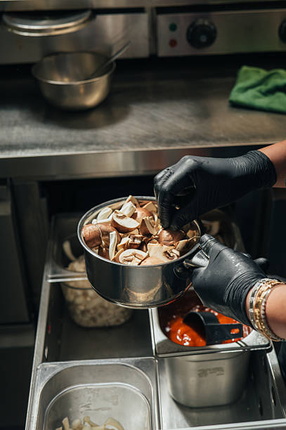 Chef holding saucepan with sliced mushrooms in restaurant kitchen