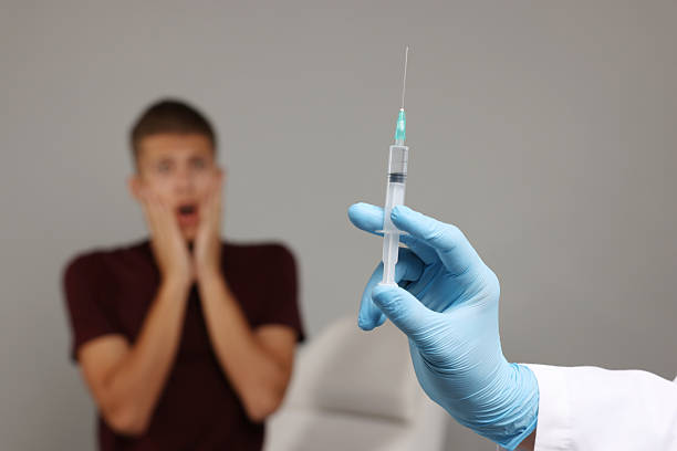 istock Needle phobia. Doctor with syringe near scared man on grey background, selective focus 2225402689