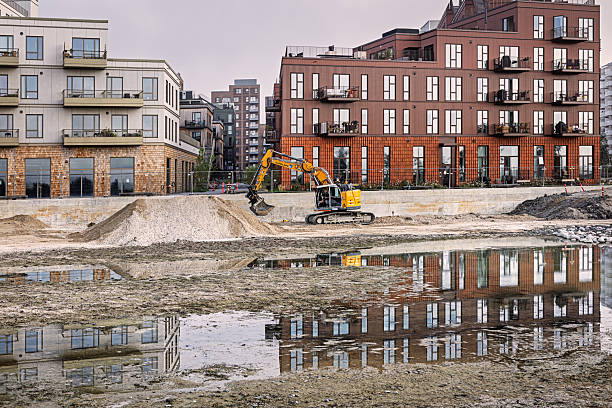 Ørestad, Copenhagen, Denmark - July 15th 2025:  A big digger is deepening an artificial lake in front of a modern housing development. The photo was taken in southern Ørestad, a newly built suburb of Copenhagen just twenty minutes from City Hall Square.