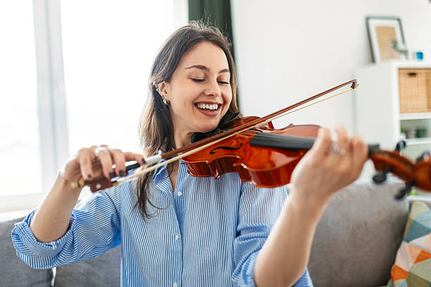Focused Young Woman Practicing Violin at Home