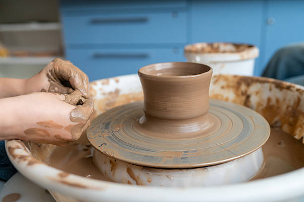 istock Child shaping wet clay into cup on spinning wheel 2225408144