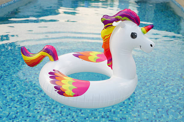 istock A bright, inflatable unicorn float with colorful mane and tail bobs in a shimmering blue swimming pool. 2225409314