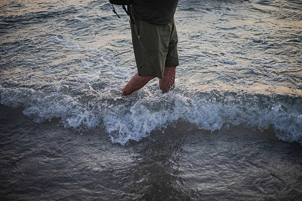 A tourist walks along the shore, wading through the water