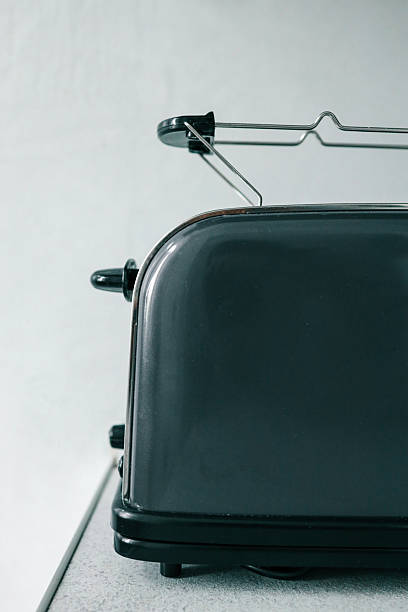 istock Side view of a sleek black toaster on a kitchen countertop with a minimalist light background. The design highlights its modern, compact shape and glossy surface 2225412173