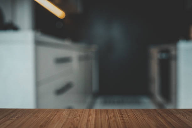 istock Wooden tabletop with blurred modern kitchen in the background. Minimalist design with black and white cabinetry, creating a clean and stylish home interior 2225412176