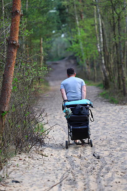 Gdansk, Poland - 18 April, 2025: A person pulling a cart full of equipment on a sandy path through the forest.