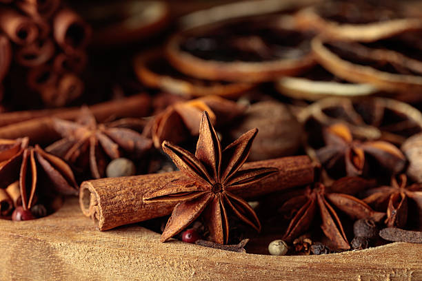 Various Christmas spices with dried citrus slices on wooden tray.