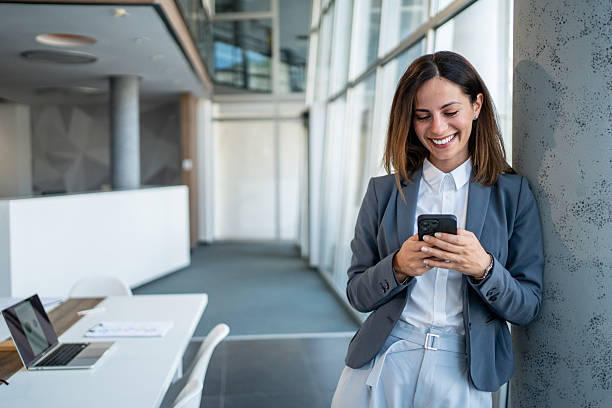 istock Businesswoman smiling while using mobile phone in modern office 2225412995