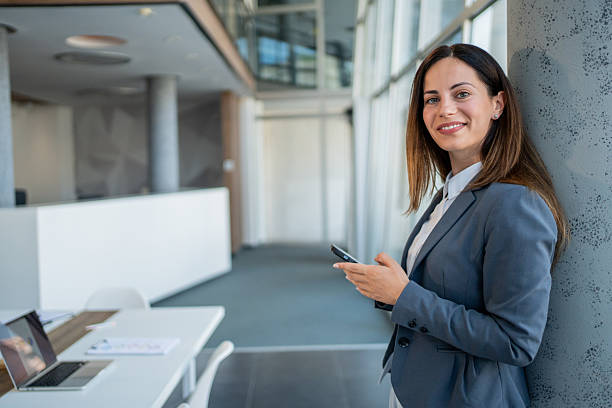 istock Businesswoman using smartphone in modern office hall 2225413279