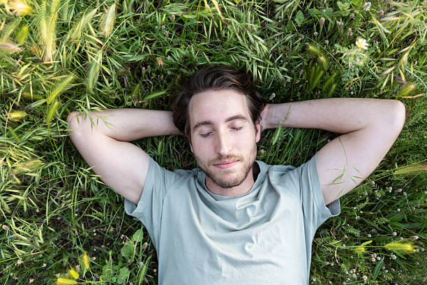 istock A man lying on green grass with eyes closed and peaceful expression 2225418521