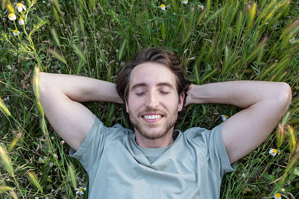 istock A man lying on green grass with eyes closed and peaceful expression 2225418577