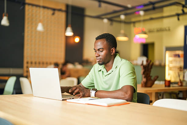 istock Focused African American Freelancer Using Laptop and Smartphone at Coffee Shop 2225421699