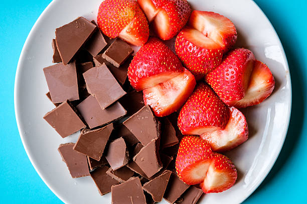 London UK, July 15 2025, Sliced Fresh Organic Strawberries With Broken Squares Of Milk Chocolate