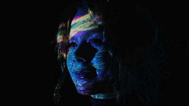 Colorful light reflections on a woman face in dark background