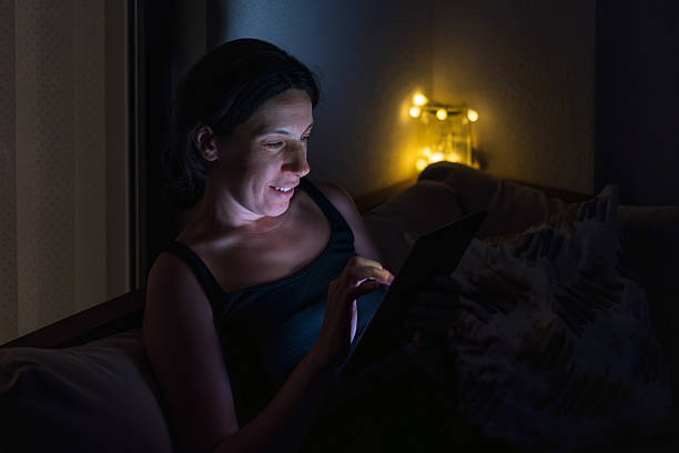 istock Woman Using Tablet on Balcony Sofa at Night with Cozy Lights 2225434843