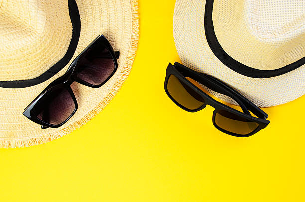 istock Two light beach hats with two sunglasses on yellow summer background 2225435083