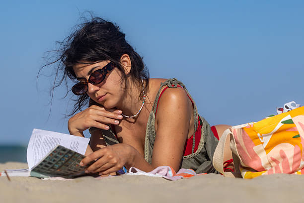 istock Girl reading book on the beach 2225435745