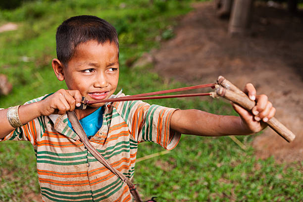 Child playing with a slingshot outdoors, aiming and having fun