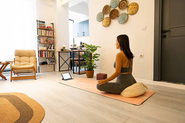istock Young woman practicing yoga at home following online class on tablet 2225438653
