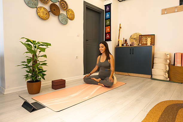 istock Young woman practicing yoga at home following online class on tablet 2225438656
