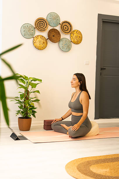 Young woman practicing yoga at home following online class on tablet