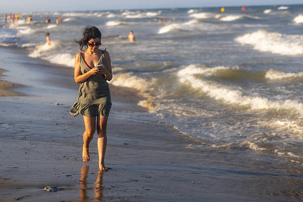 Girl with Phone on a Windy Beach