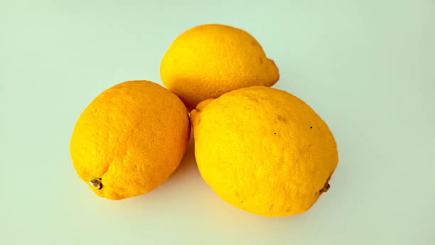 istock Fresh lemons in hand and on table, isolated on light background 2225441357