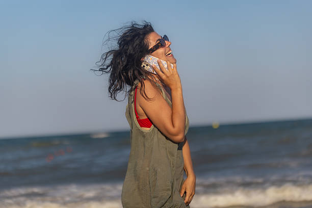 istock Young Woman Talking on Phone at Beach 2225441509
