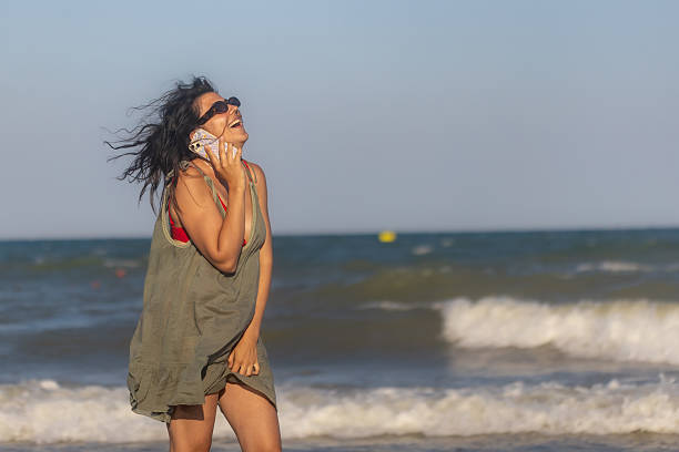 istock Young Woman Talking on Phone at Beach 2225441515