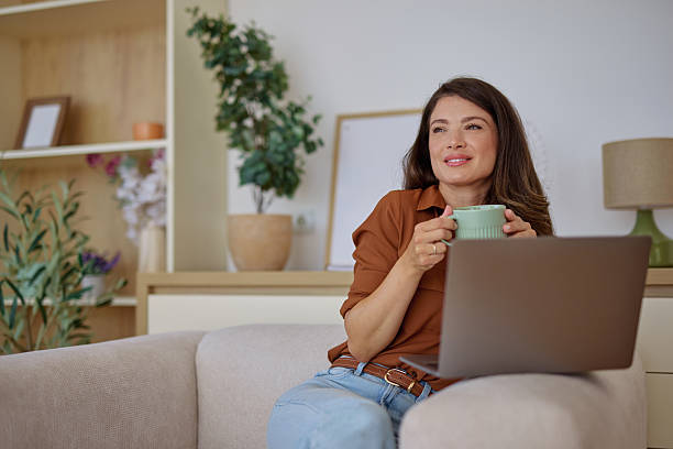 istock Woman enjoying a cup of coffee while working from home on her laptop 2225445543