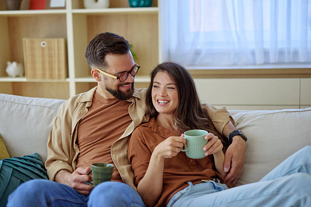 istock Young couple relaxing on sofa, drinking tea and enjoying time together at home 2225445663