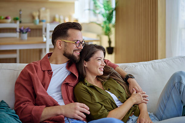 istock Young couple relaxing on sofa embracing and smiling at home 2225445998
