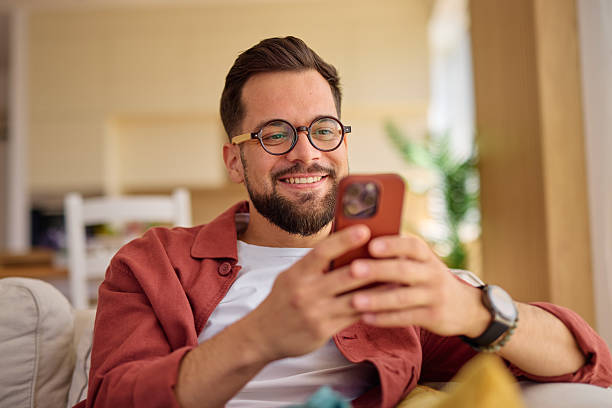 istock Young man relaxing on sofa using mobile phone at home 2225446091