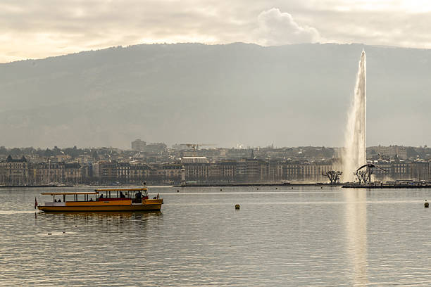 Geneva, Switzerland, Europe – April 7, 2025: General view of Lake Geneva waterfront with boats, yachts, and historic buildings along the Quai du Mont-Blanc during a sunny spring day.