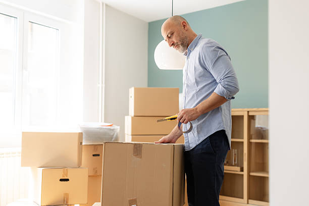 istock Man packing cardboard boxes in a bright home interior during a moving process 2225447850