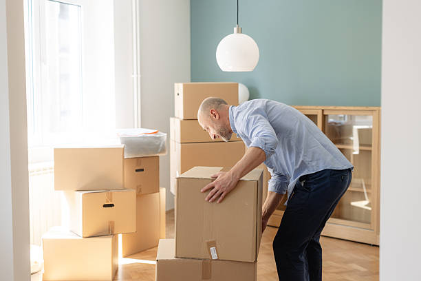 istock A man is lifting a cardboard box in an organized room with packed items during relocation 2225447856