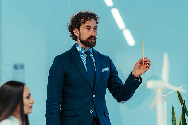 istock Businessman explaining sustainable project with miniature wind turbine model 2225451387